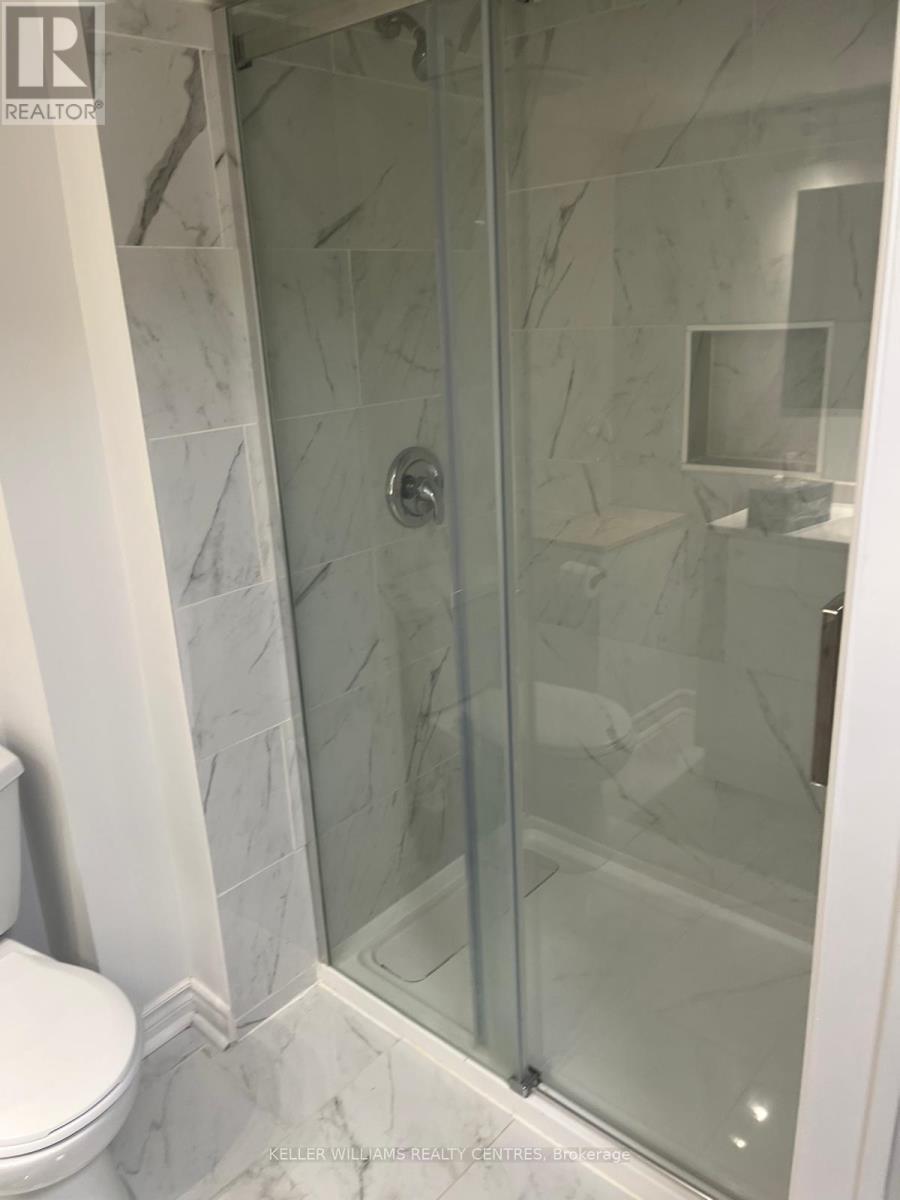 A bathroom with a glass shower door and a white toilet.