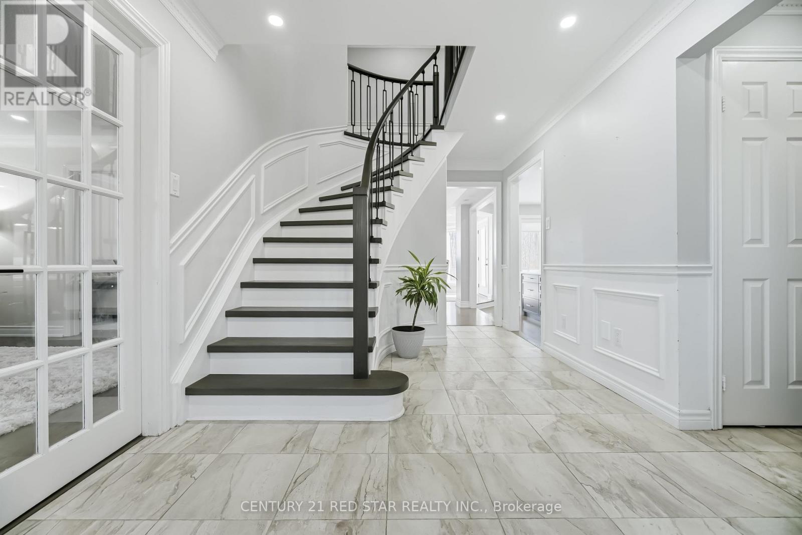 A spacious hallway with a staircase and a potted plant.