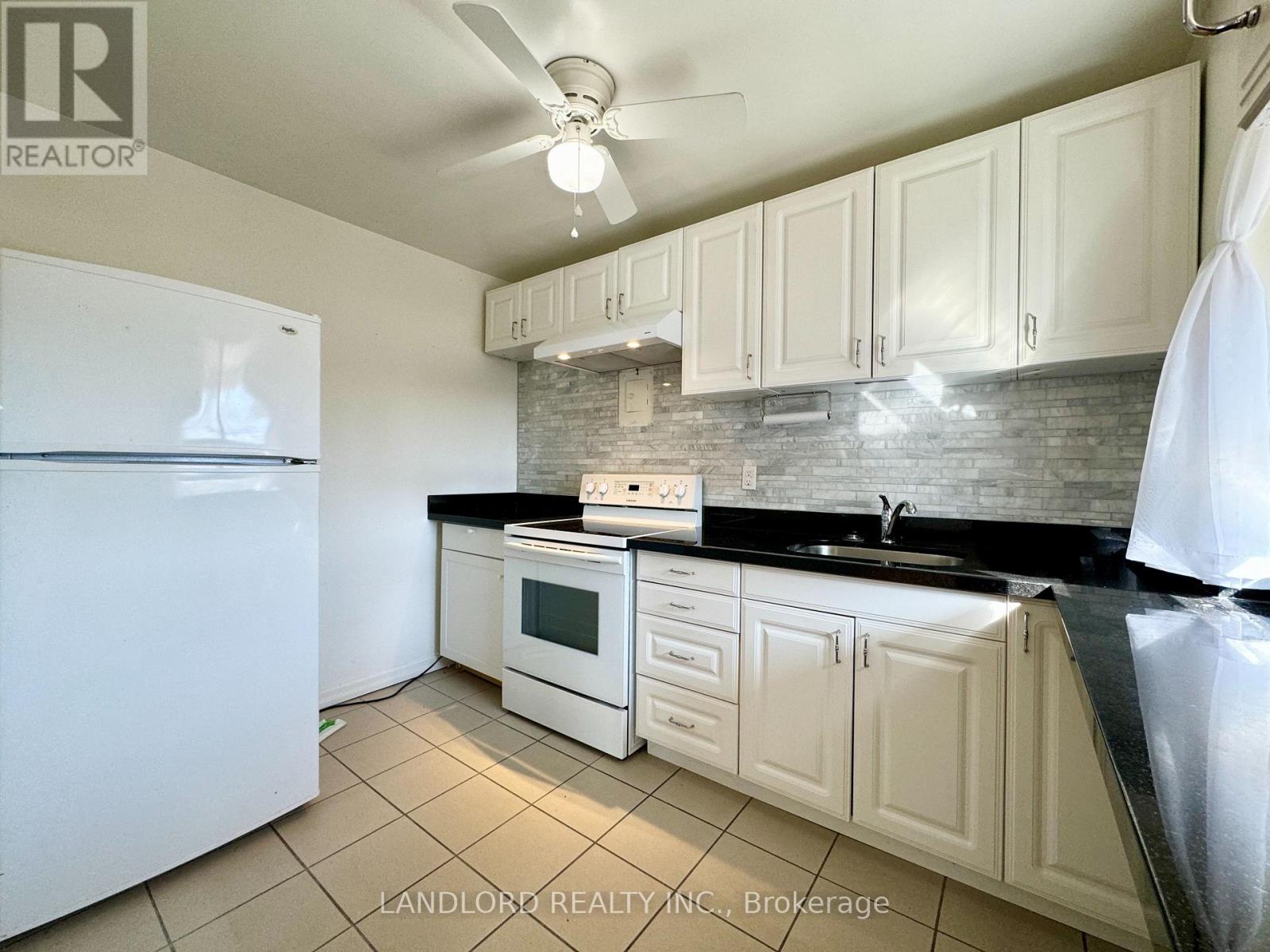 A kitchen with white cabinets and a black countertop.