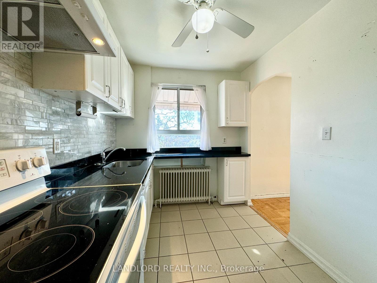 A kitchen with a black stove top oven and white cabinets.