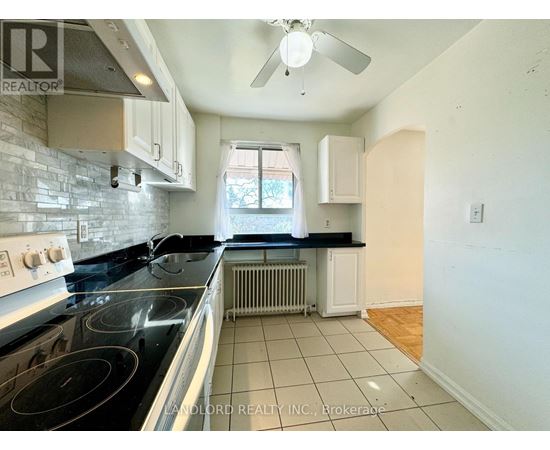 A kitchen with a black stove top oven and white cabinets.