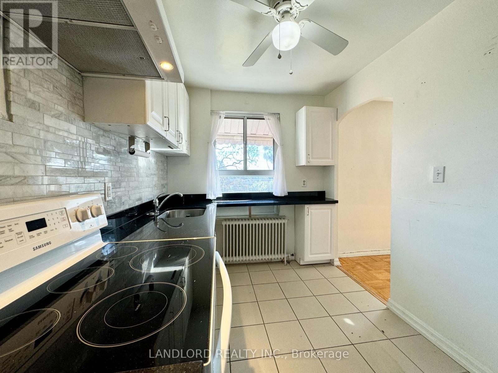 A kitchen with a stove top oven and a fan on the ceiling.