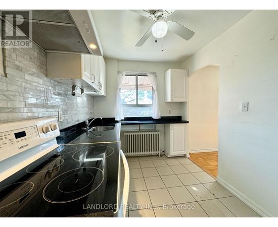 A kitchen with a stove top oven and a fan on the ceiling.
