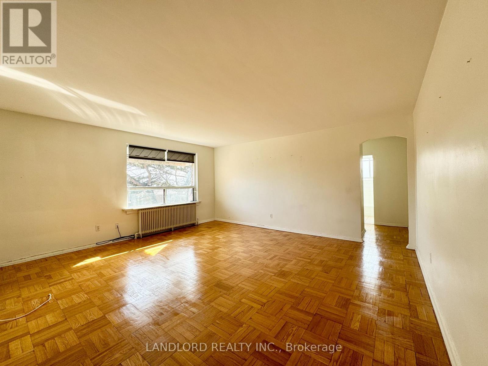A room with wooden flooring and a window with blinds.