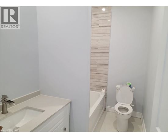 A white toilet in a bathroom with a white sink.