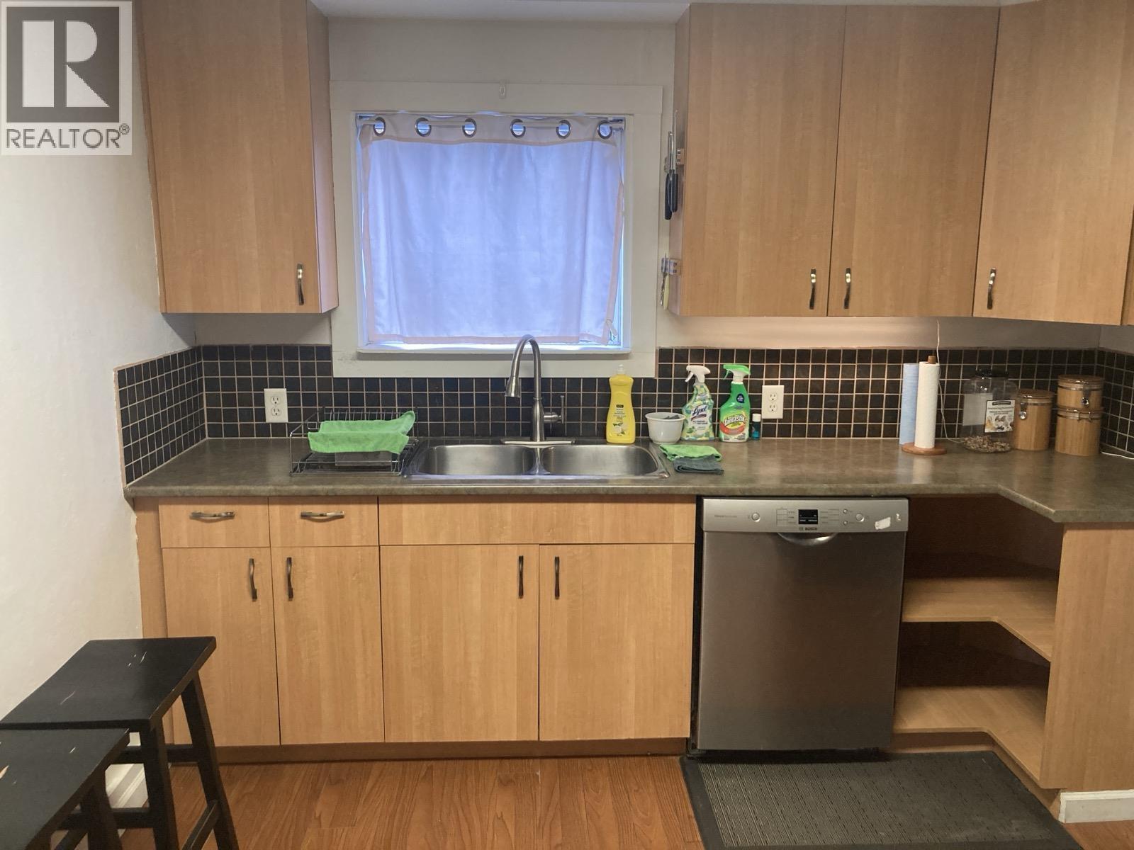 A kitchen with wooden cabinets and a black dishwasher.