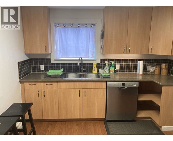 A kitchen with wooden cabinets and a black dishwasher.