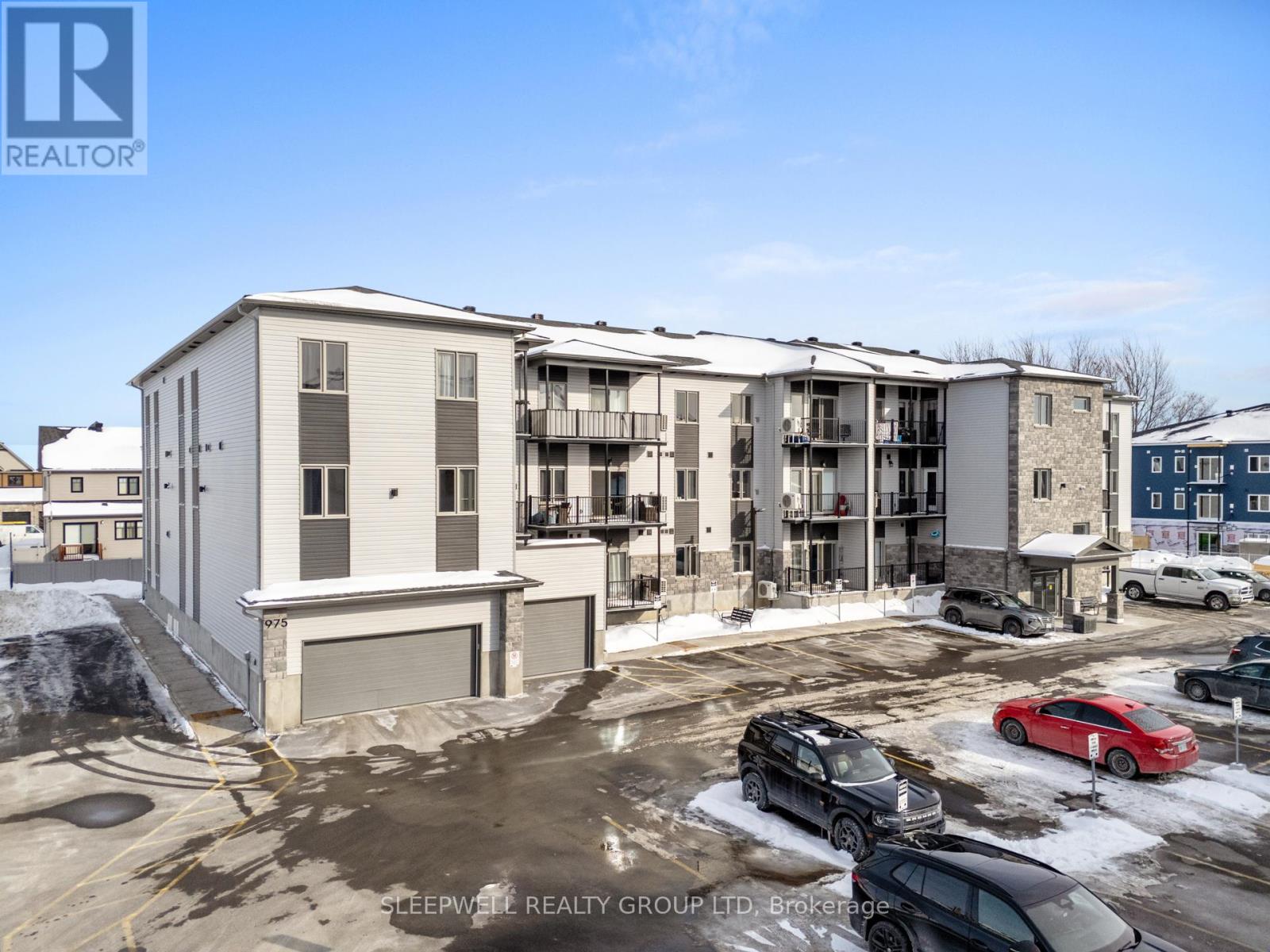 A real estate company's photo of a residential complex with cars parked in front.