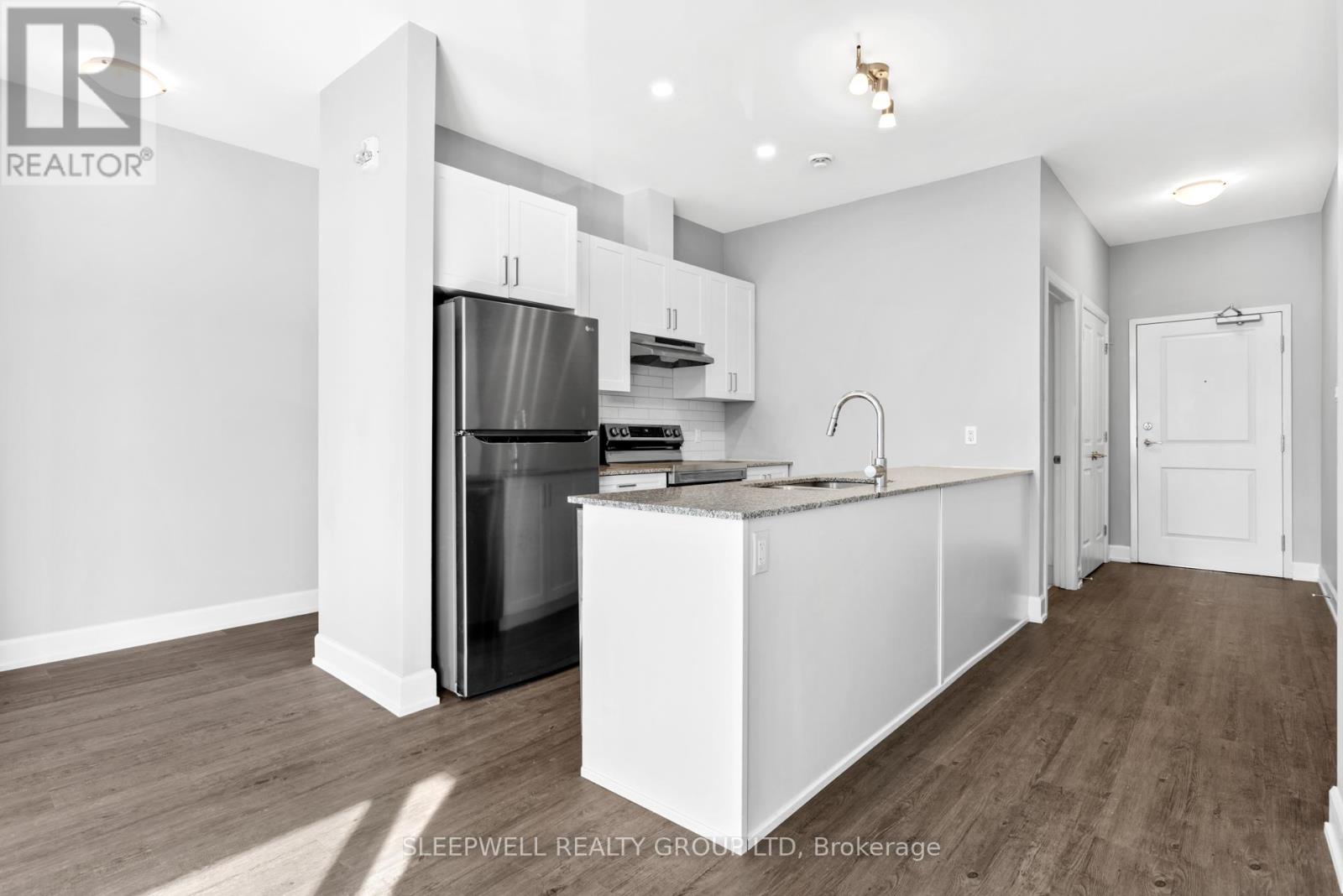 A kitchen with white cabinets and a stainless steel refrigerator.