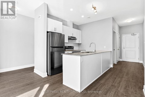 A kitchen with white cabinets and a stainless steel refrigerator.