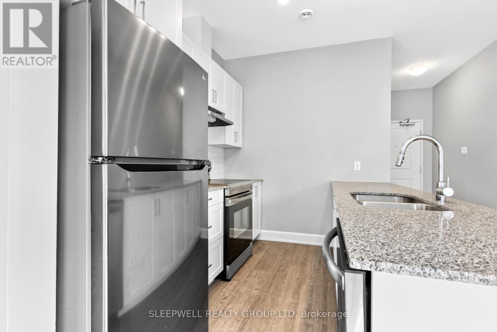 A modern kitchen with a granite countertop and stainless steel appliances.
