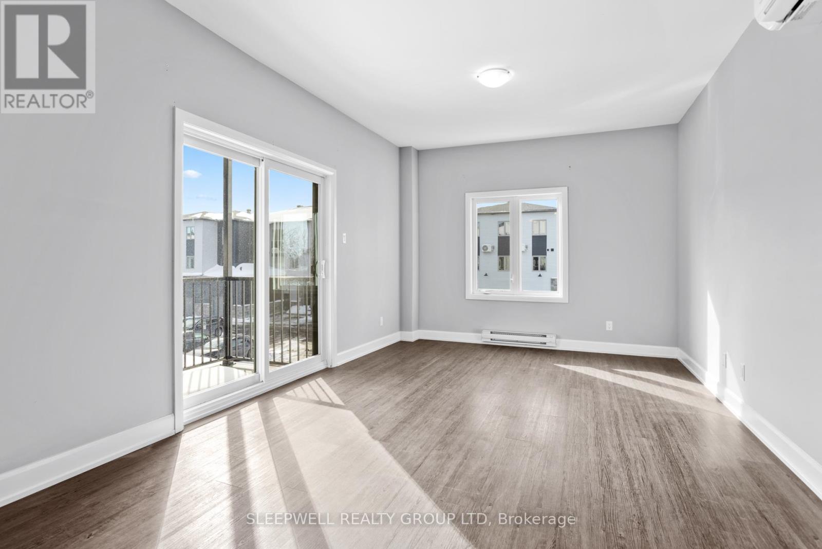 A spacious room with a sliding glass door leading to a balcony.