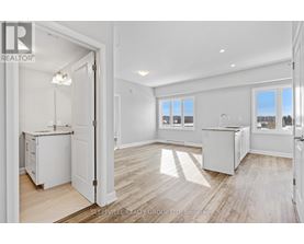 A realtor photo of a white kitchen with wood floors and a view of the outdoors through the windows.