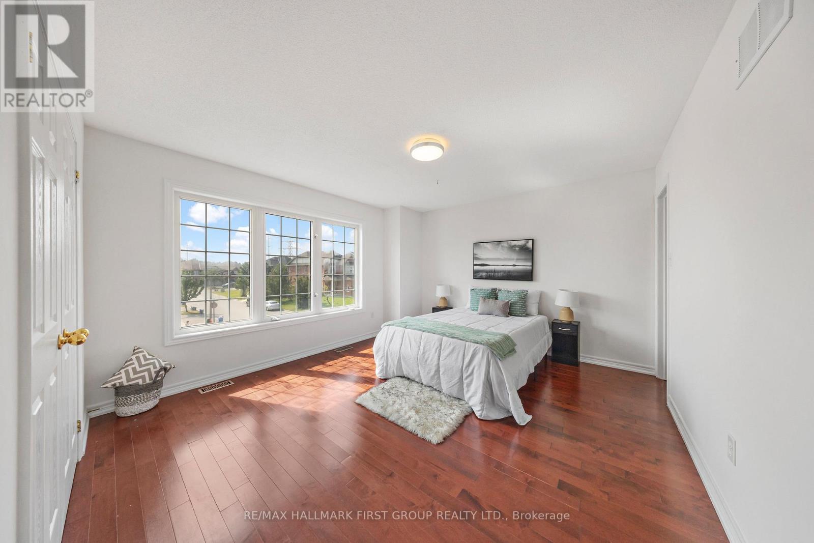 A bedroom with a bed, a window, and a painting on the wall.