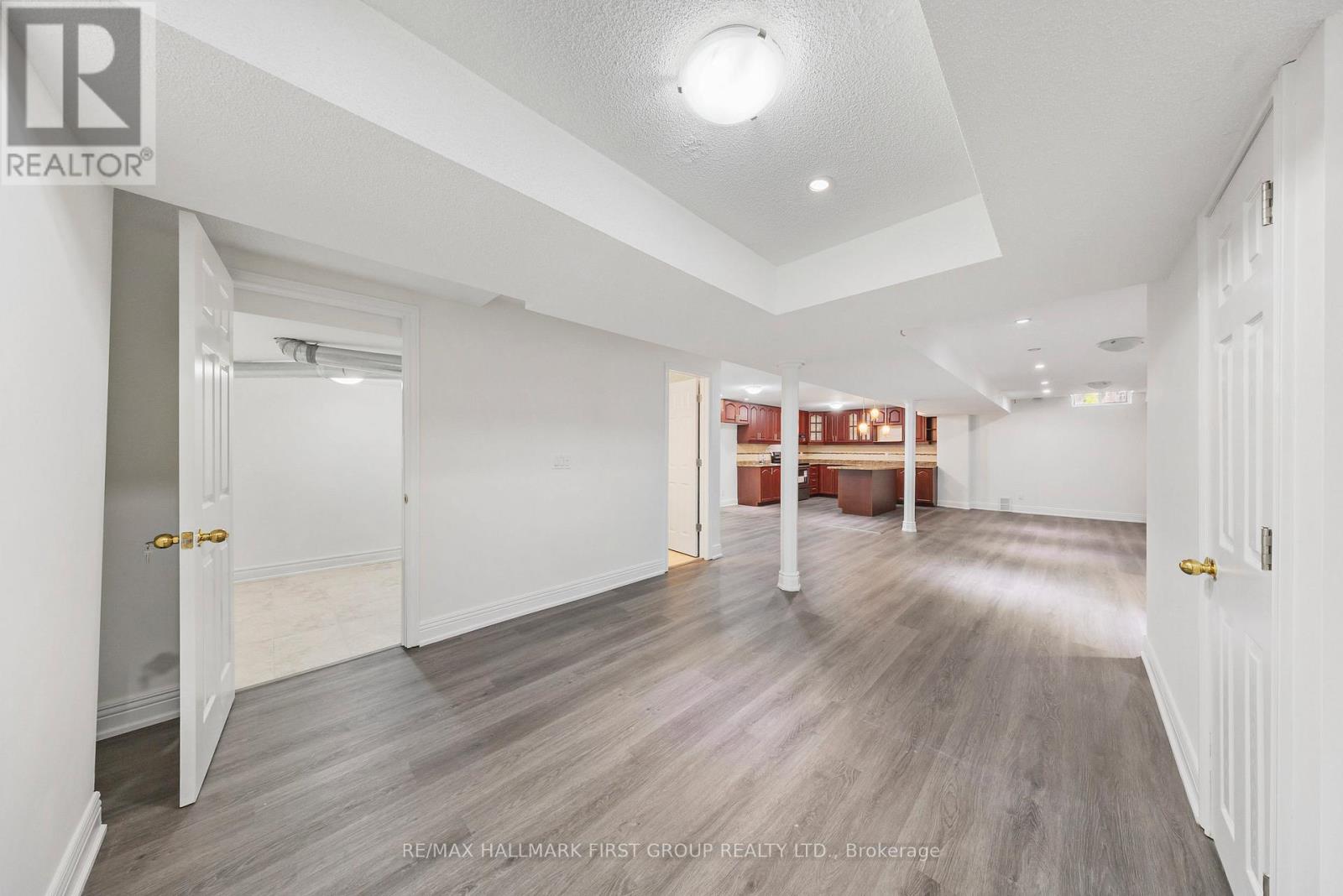 A spacious room with wooden flooring and white walls.
