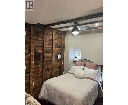 A bedroom with a bed, pillows and a wooden wall.