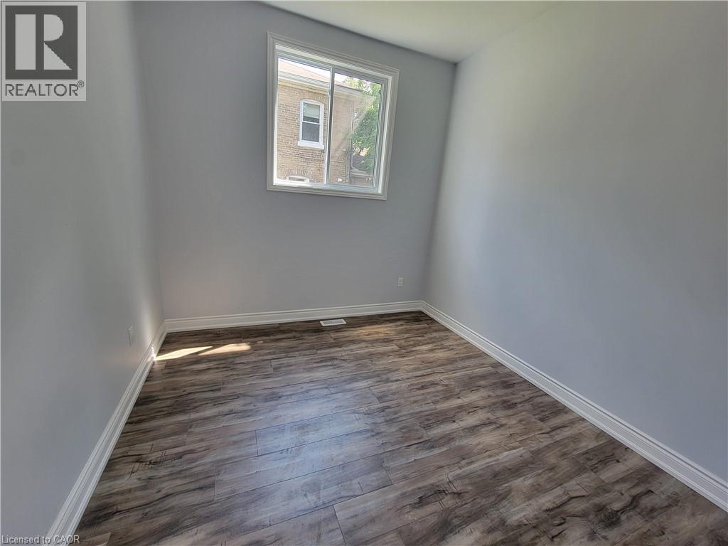 A room with wooden flooring and a window showing a building outside.