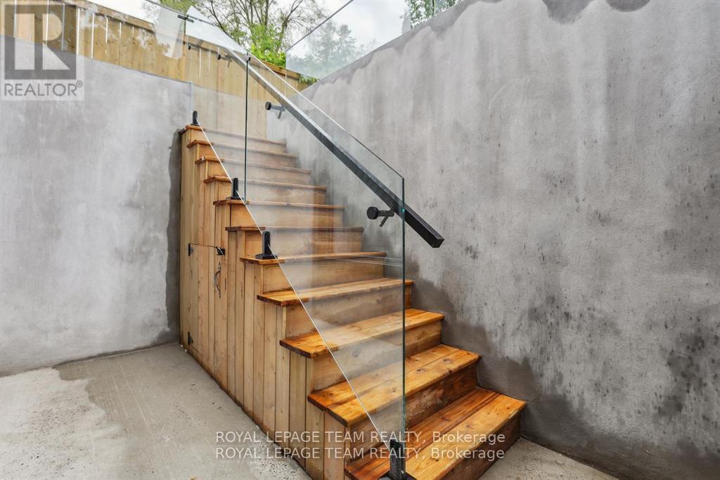 A set of wooden stairs with a metal handrail.