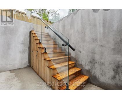 A set of wooden stairs with a metal handrail.