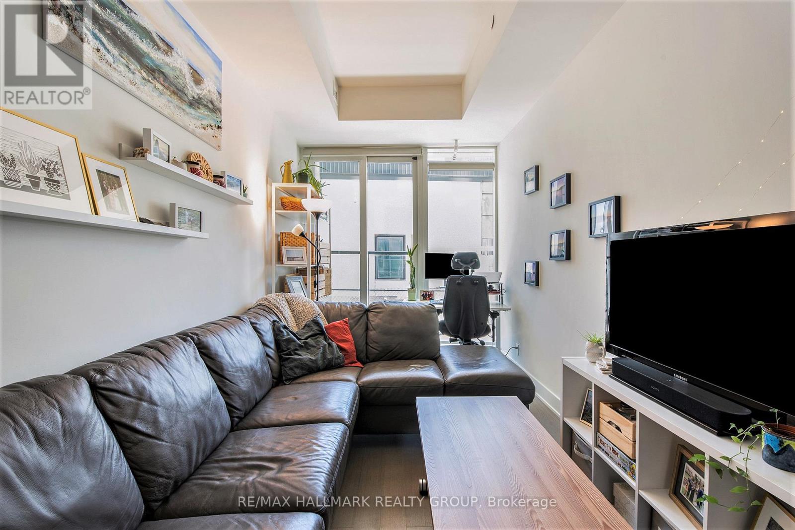 A living room with a black leather couch and a flat screen TV.