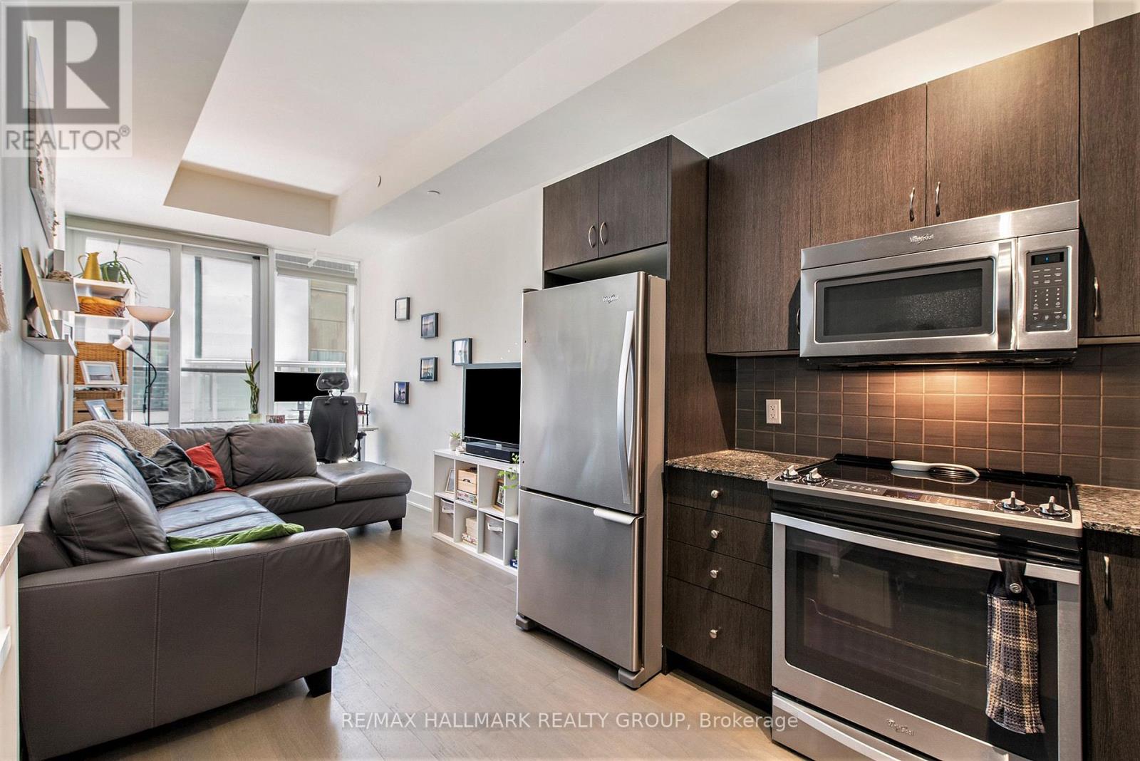 A modern kitchen with dark wood cabinets and stainless steel appliances.