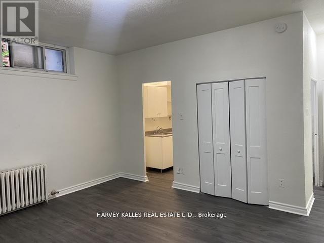 A room with a white wall and a wooden floor with a cabinet and a drawer.