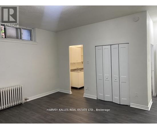 A room with a white wall and a wooden floor with a cabinet and a drawer.