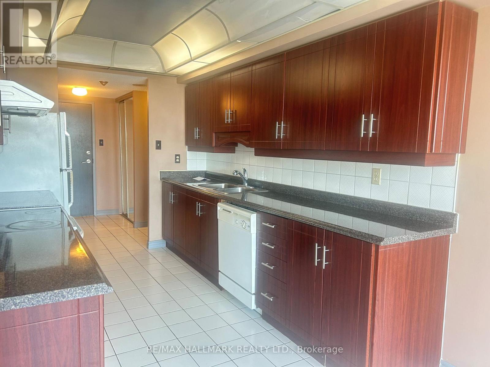 A kitchen with dark wood cabinets and white appliances.