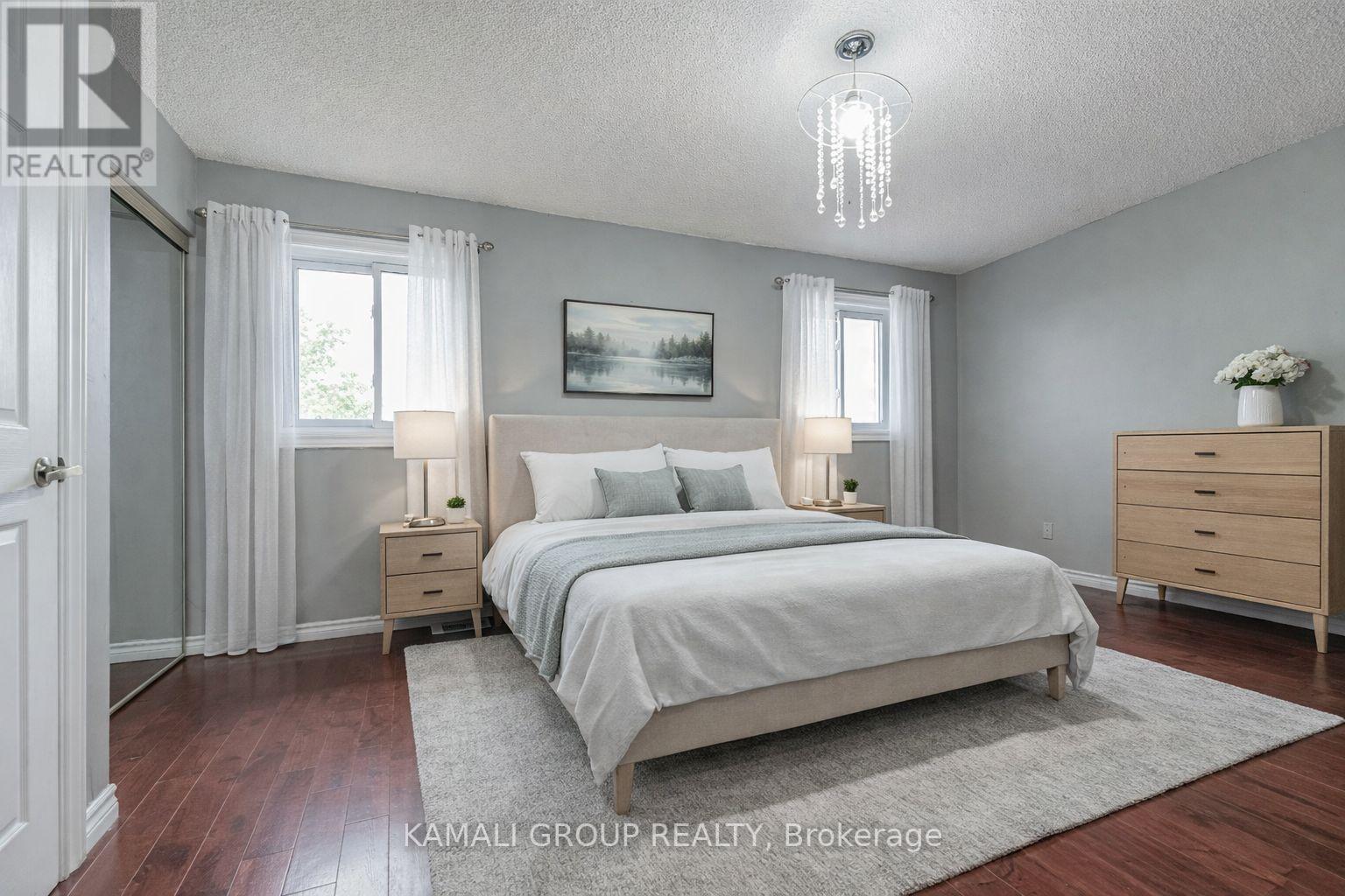 A bedroom with a large bed, two nightstands, and a dresser.