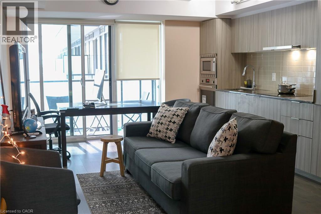A living room with a grey couch and a wooden stool.