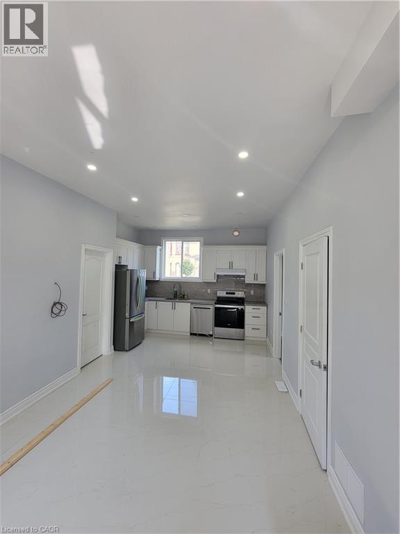 A white kitchen with a refrigerator, sink, and cabinets.