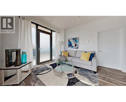 A living room with a grey couch, a glass table, and a rug.