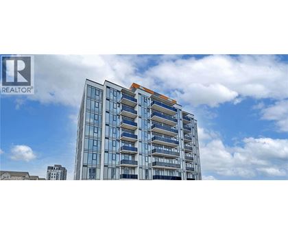 A tall building with a glass facade and a brown roof is shown under a blue sky with clouds.