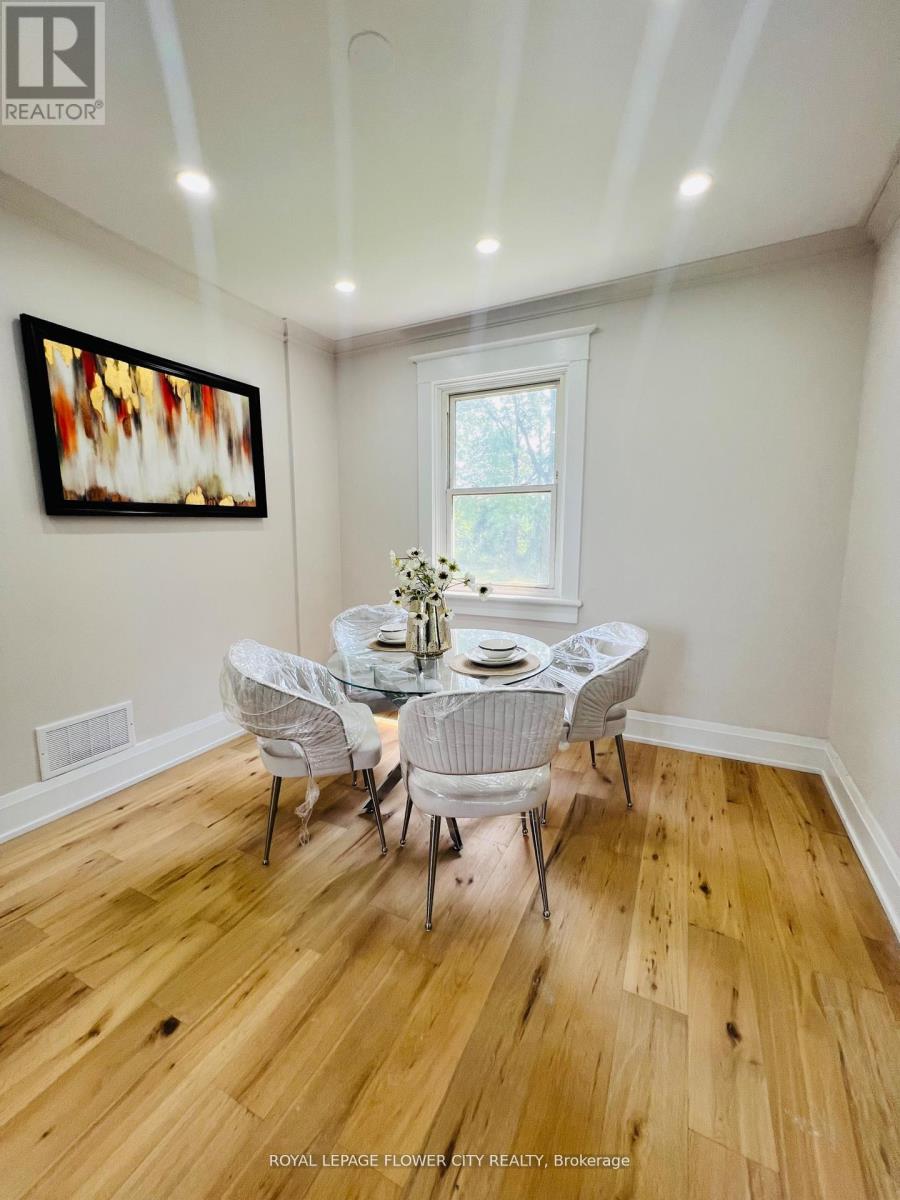 A dining room with a wooden floor and white chairs.