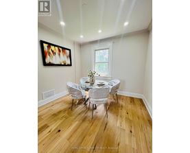 A dining room with a wooden floor and white chairs.
