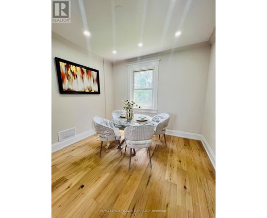 A dining room with a wooden floor and white chairs.