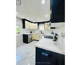 A modern kitchen with black and white cabinets and a marble floor.