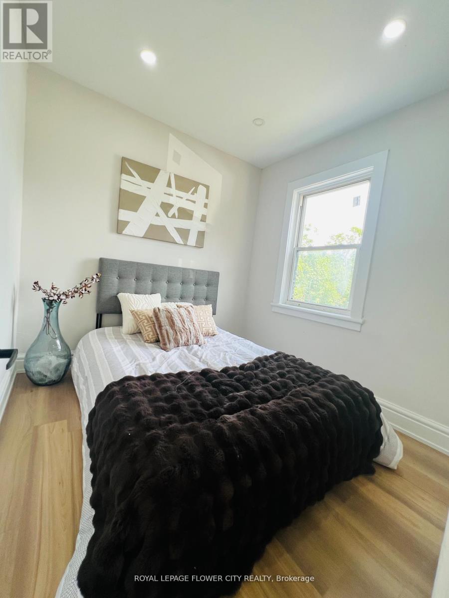 A bedroom with a large bed and a vase on the nightstand.