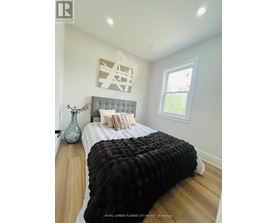 A bedroom with a large bed and a vase on the nightstand.