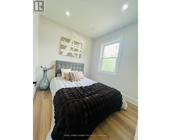 A bedroom with a large bed and a vase on the nightstand.