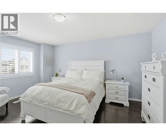 A bedroom with a white bed and a white nightstand.