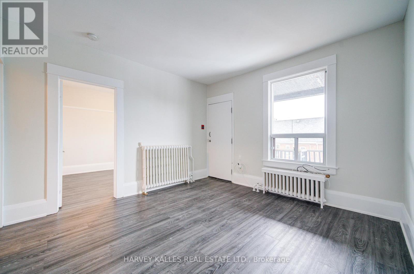 A spacious room with wood flooring and white walls.