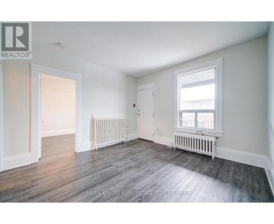 A spacious room with wood flooring and white walls.