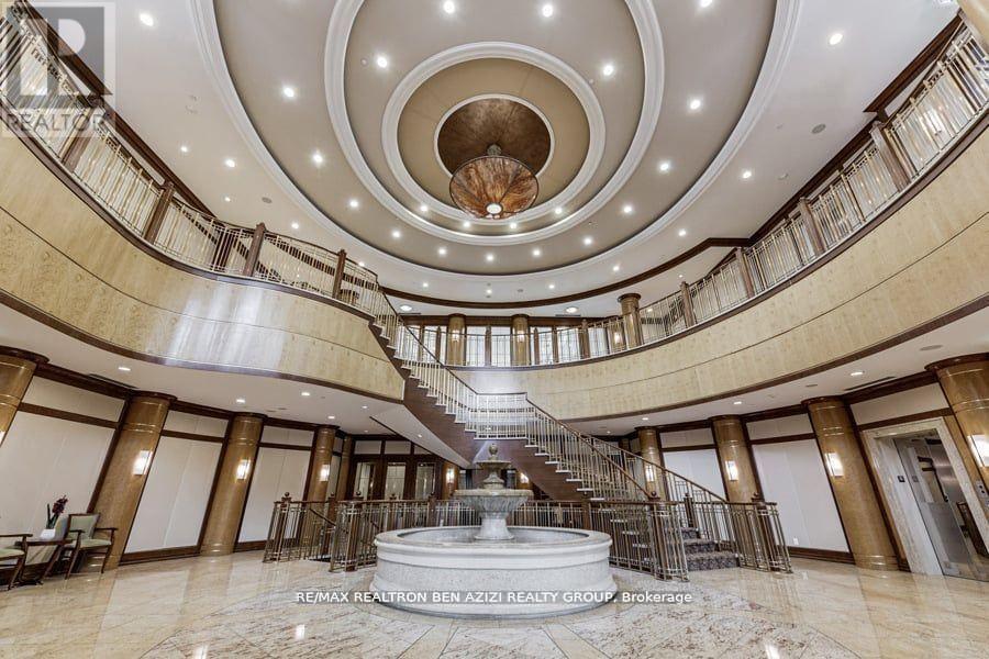 A grand staircase with a circular ceiling and a fountain in the middle of a spacious lobby.