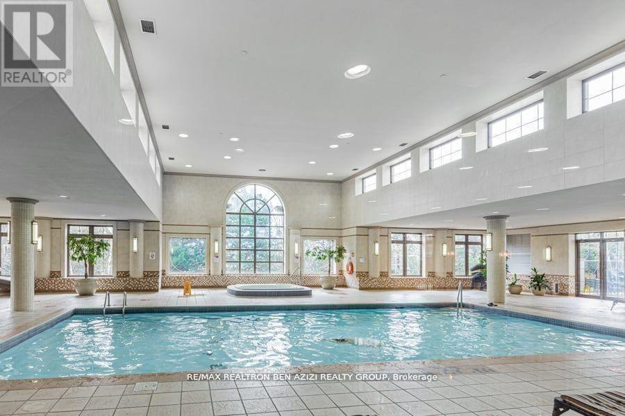 A large indoor swimming pool in a spacious room with a high ceiling and large windows.