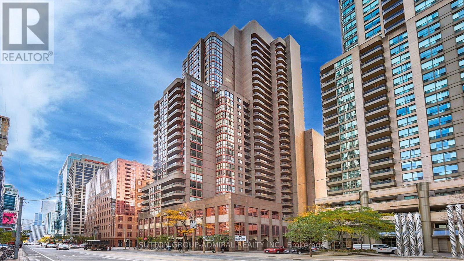 A tall building with many windows is in the foreground of a city street.