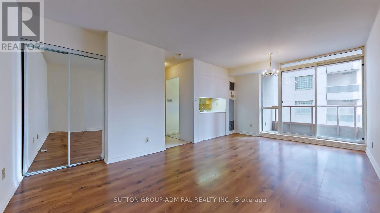 A spacious room with wood flooring and sliding glass doors.