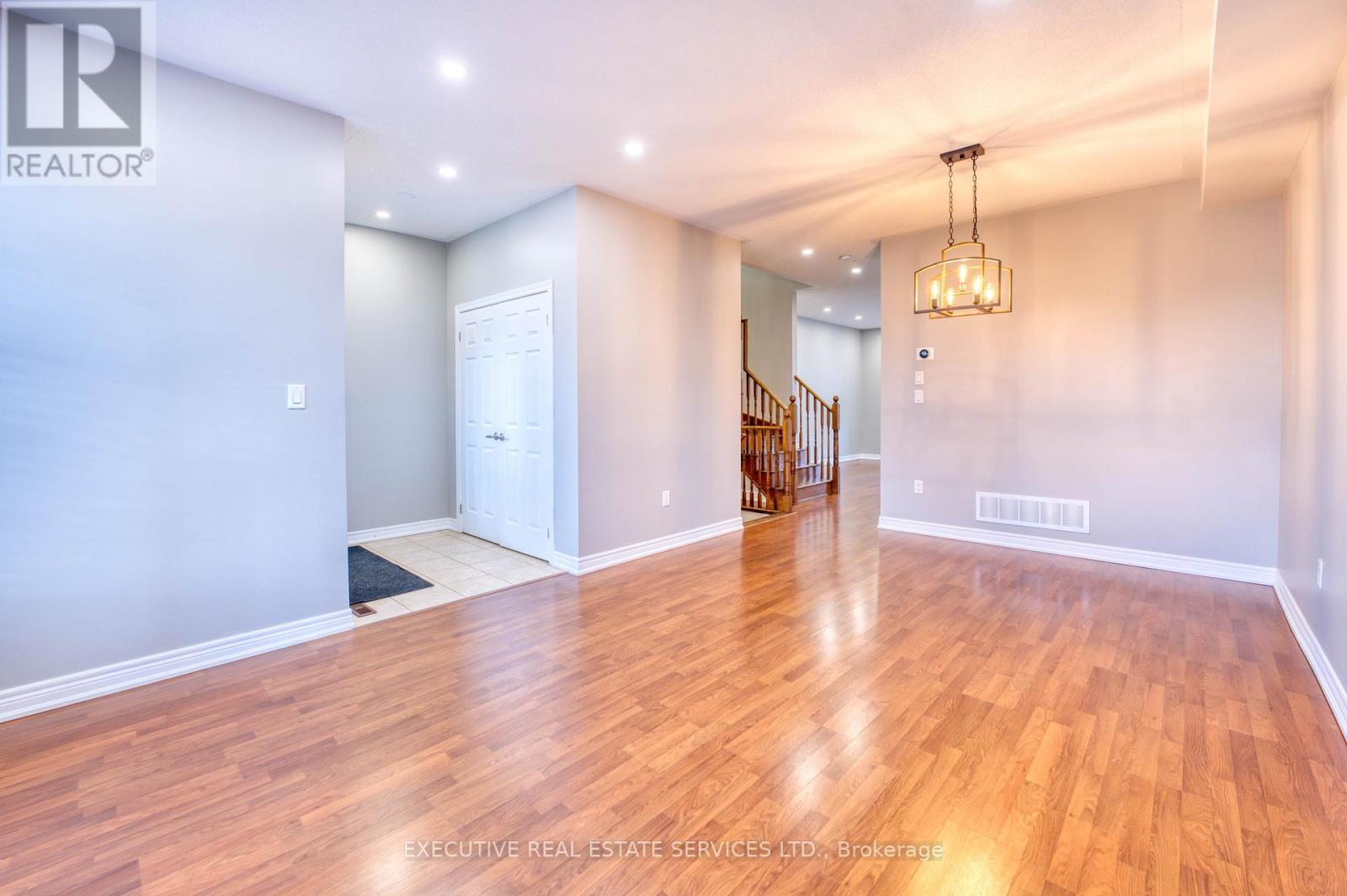 A spacious room with wooden flooring and a chandelier hanging from the ceiling.