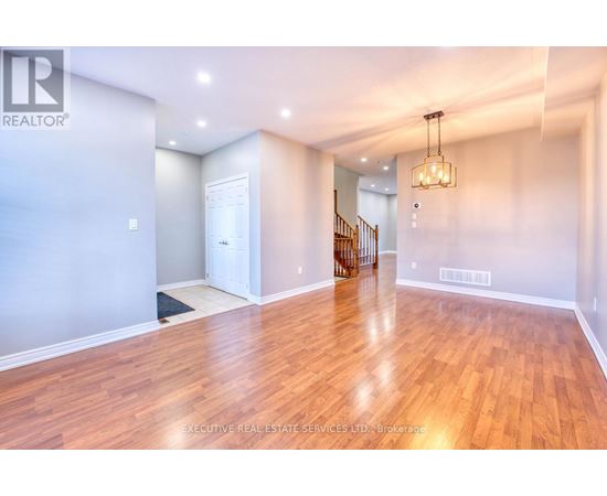 A spacious room with wooden flooring and a chandelier hanging from the ceiling.