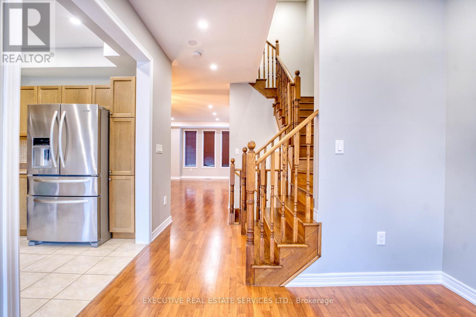 A spacious kitchen with a refrigerator and a staircase.